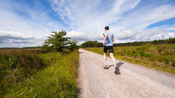 Man running on a trail next to grass